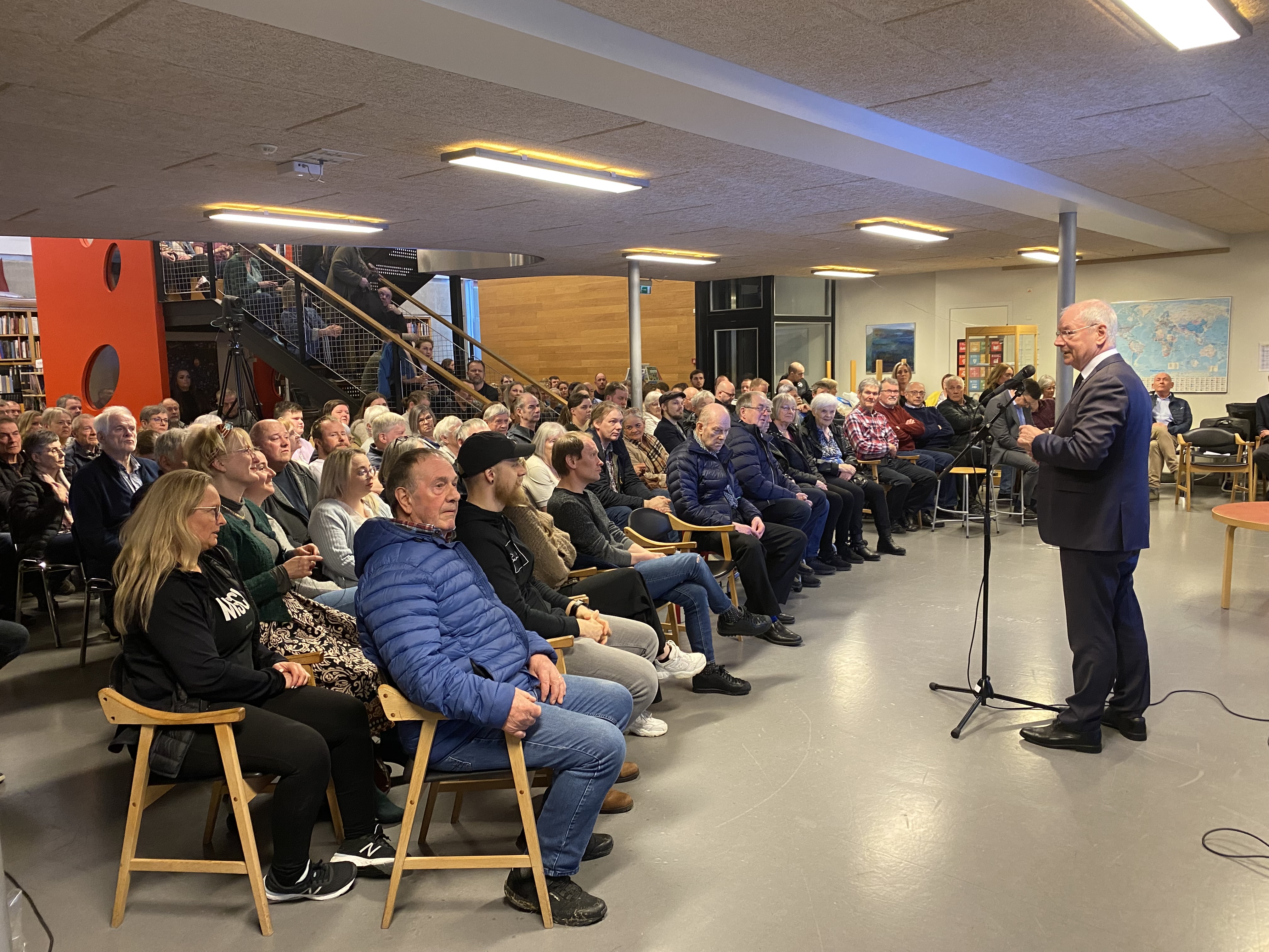 a person speaking to a group of people in a room